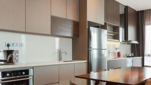 A modern kitchen with stainless steel appliances, a dining area with a wooden table, and a large window with curtains.