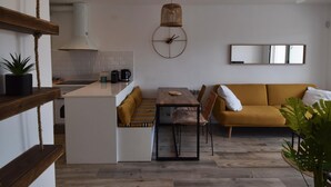 Une cuisine moderne avec des meubles blancs, un îlot central en bois et un luminaire suspendu.