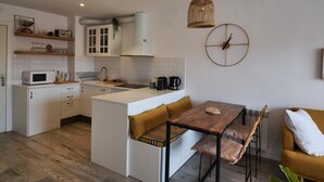 Une cuisine moderne avec des meubles blancs, une table à manger en bois avec des bancs et un luminaire suspendu.