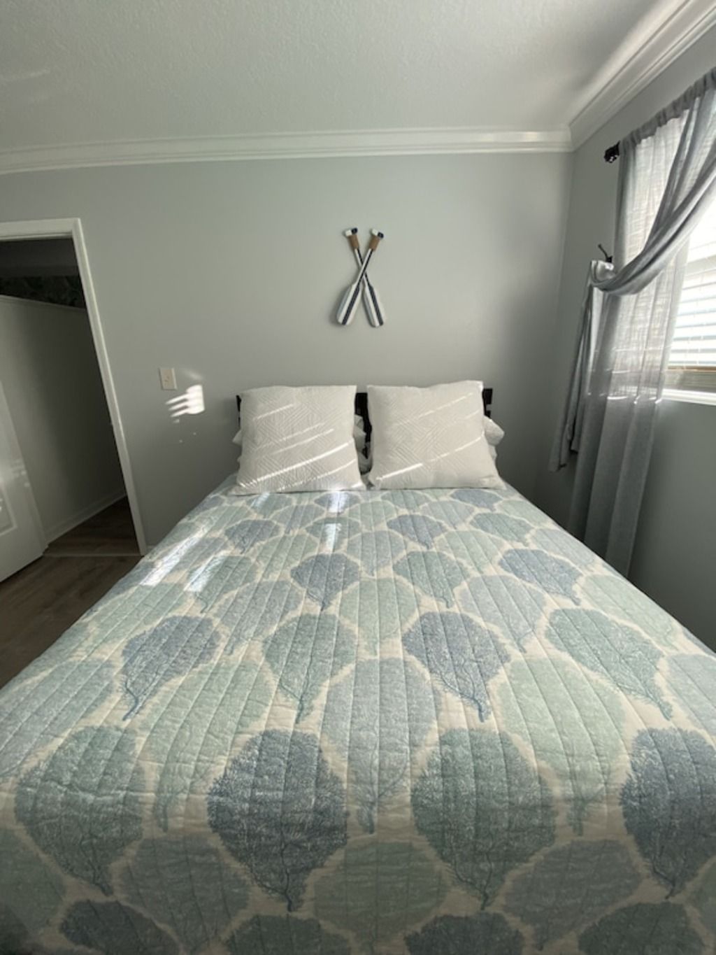 Une chambre à coucher avec un lit, une porte et une fenêtre avec des rideaux.