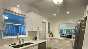 A modern kitchen with white cabinetry, a built-in dishwasher, and a stainless steel refrigerator. - River Beach Retreat: with Tiki Bar, Fire Pit, Hot Tub & Clear Kayak (Spring Hill)