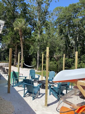 Outdoor seating with chairs and a table, surrounded by trees and a hammock. - River Beach Retreat: with Tiki Bar, Fire Pit, Hot Tub & Clear Kayak (Spring Hill)
