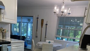 A modern kitchen with white cabinetry, a stainless steel sink, and a dining area with a table and chairs. - River Beach Retreat: with Tiki Bar, Fire Pit, Hot Tub & Clear Kayak (Spring Hill)