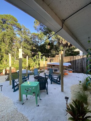 An outdoor patio area with a covered seating arrangement, a table, and chairs. - River Beach Retreat: Tiki Bar, Hot Tub, Kayaks&BBQ (Spring Hill)