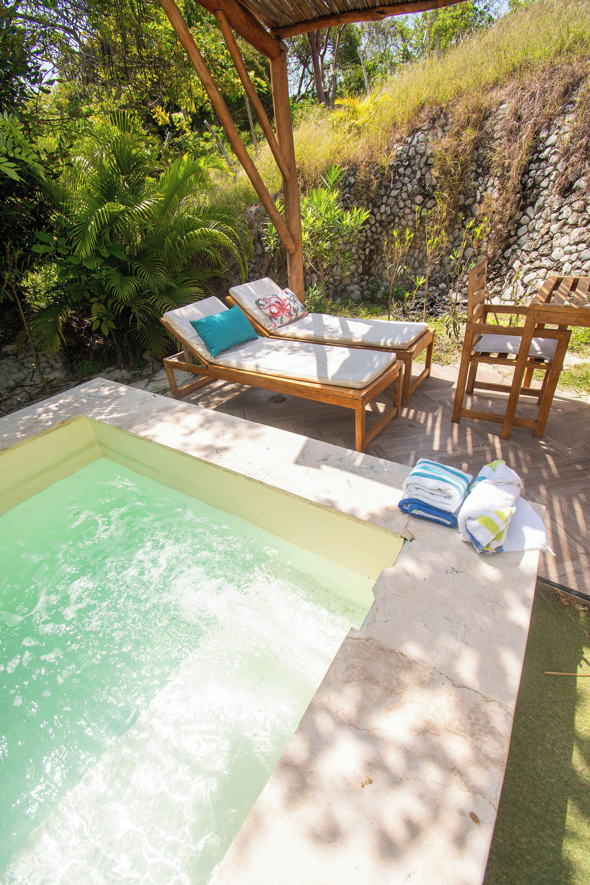 A pool area with lounge chairs and a small hot tub.