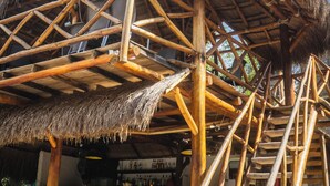 A wooden structure with thatched roofs and a stone wall. - AMALIFE Beach Club & Hotel  (Cartagena)