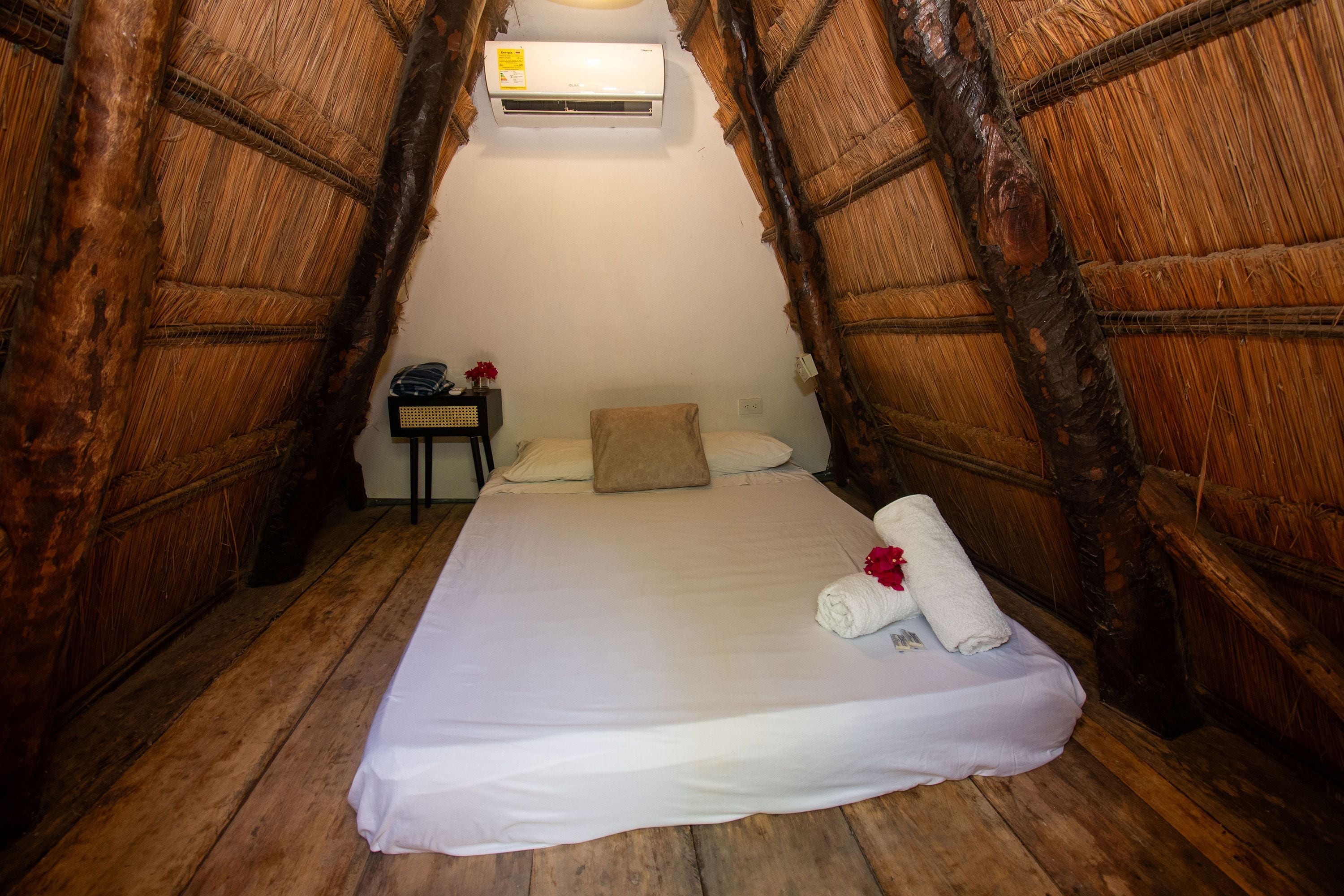 A room with a bed, a nightstand, and an air conditioning unit.
