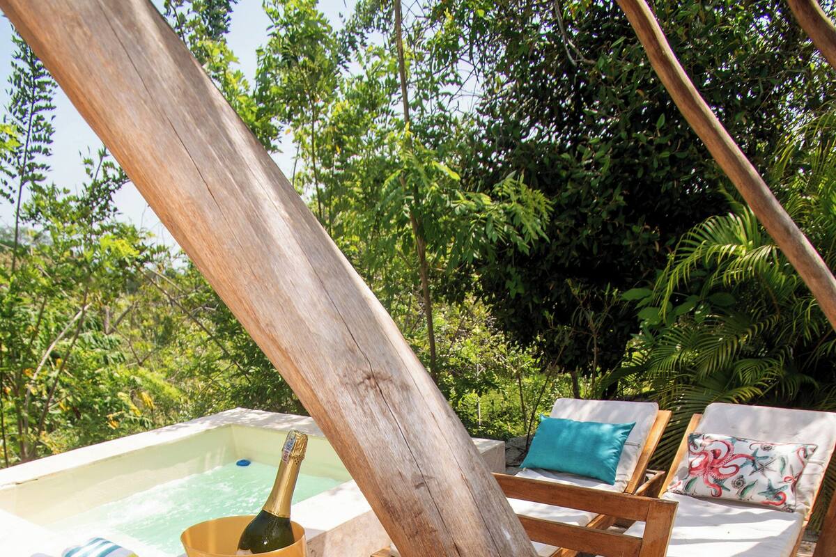 A wooden deck with a hot tub, a bottle of champagne, and a plate of fruit.