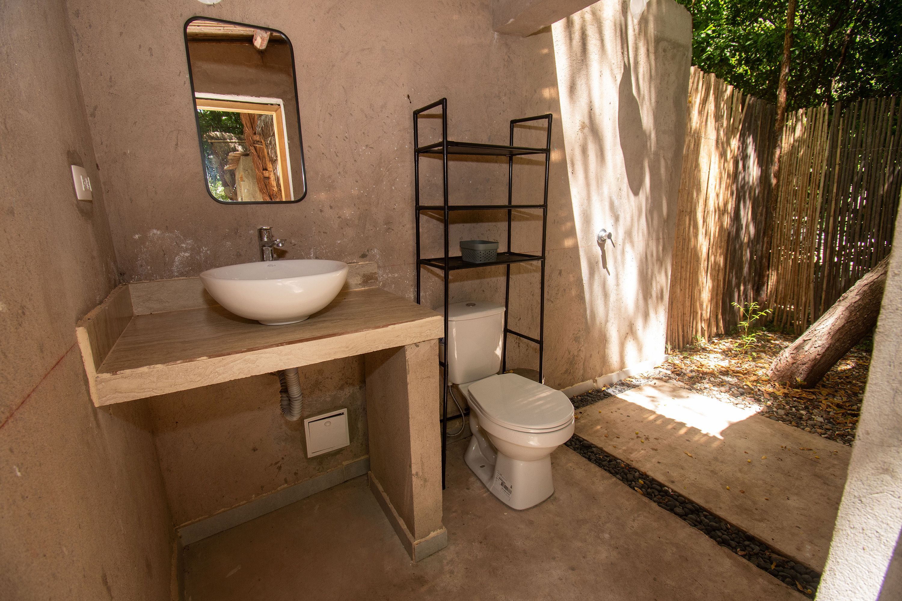 Un baño con un lavamanos blanco, un inodoro y un espejo.