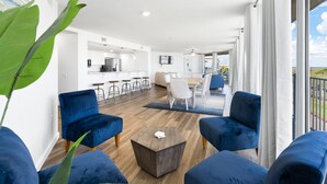 Un soggiorno moderno con divani blu, un tavolino da caffè e vista sulla cucina e sulla sala da pranzo.