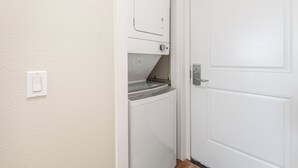 A laundry room with a washing machine, dryer, and a door. - Sandcastle Condominium Unit 102 (Port Aransas)