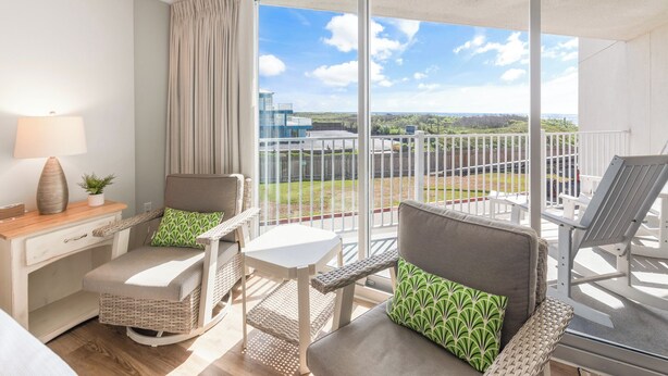 A balcony with wicker furniture, a small table, and a lamp. - Sandcastle Condominium Unit 102 (Port Aransas)