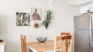A dining area with a wooden table, four chairs, a bowl, a potted plant, and artwork on the wall. - Sandcastle Condominium Unit 102 (Port Aransas)