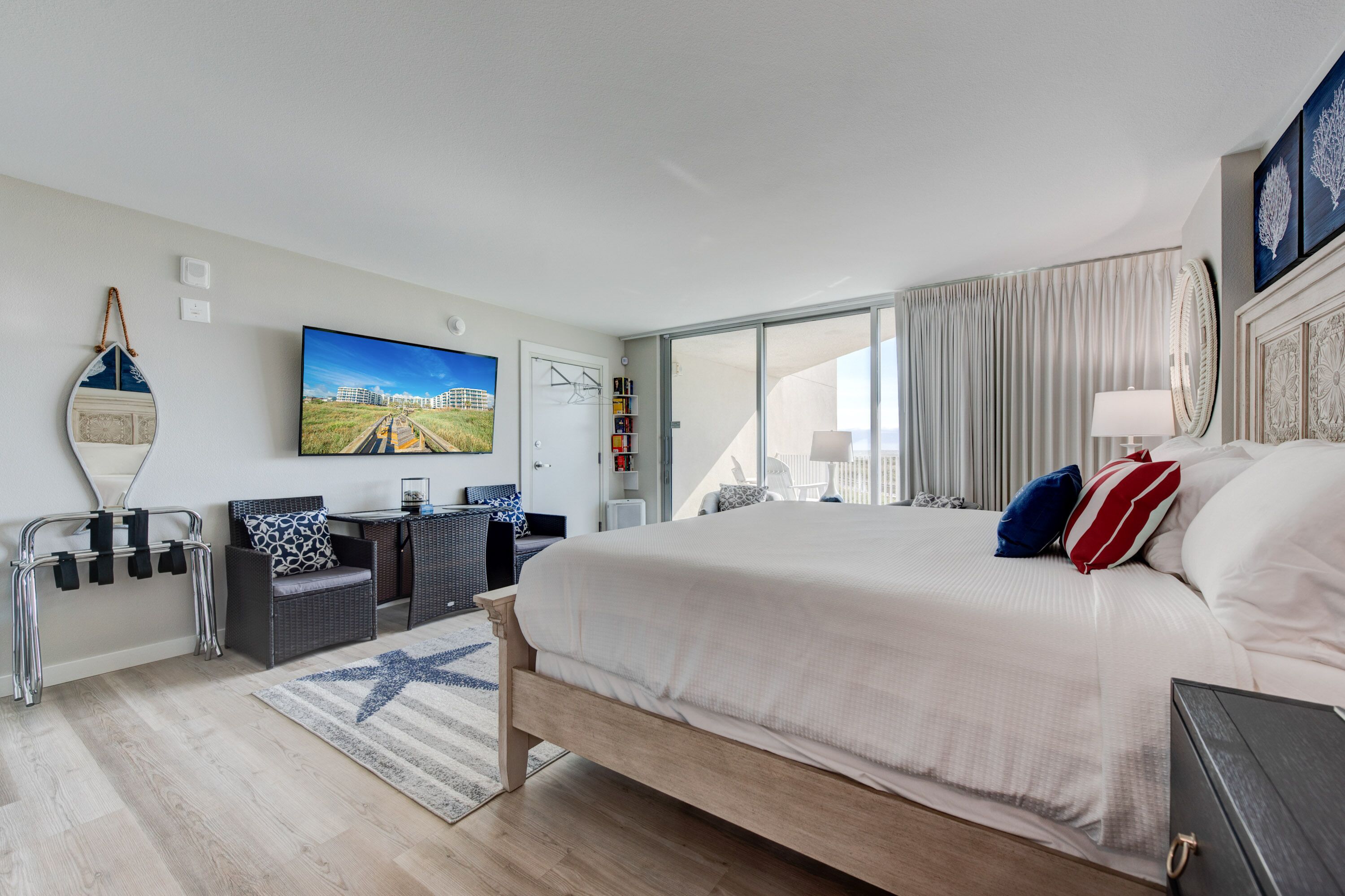 Une chambre d’hôtel moderne dotée d’un grand lit, d’une télévision à écran plat, d’un balcon avec des rideaux et offrant une vue sur le paysage urbain.