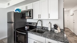 Una cucina moderna con mobili bianchi, elettrodomestici in acciaio inossidabile, un piano di lavoro in granito e un forno a microonde integrato.