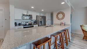 Een moderne keuken met witte kasten, roestvrijstalen apparatuur en een granieten aanrecht.