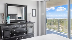 Une chambre avec une grande fenêtre, une commode et un miroir.