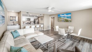 A modern living room with a sofa, coffee table, and dining area with chairs. - Sandcastle Condominiums Unit 323 (Port Aransas)