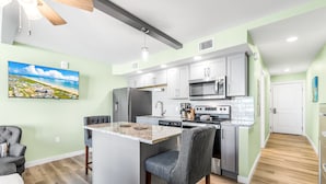 Una cucina moderna con isola centrale, elettrodomestici in acciaio inox e pareti color verde chiaro.