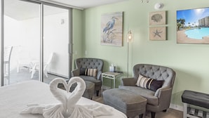 Una camera d'albergo con un letto, due poltrone, una panca, un tavolino e opere d'arte alle pareti.