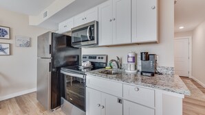 A modern kitchen with stainless steel appliances, white cabinetry, and a granite countertop. - Sandcastle Condominiums Unit 527 (Port Aransas)