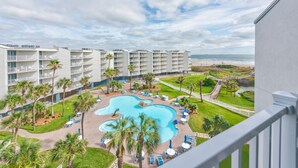 A hotel with a pool, palm trees, and a view of the beach. - Sandcastle Condominiums Unit 527 (Port Aransas)