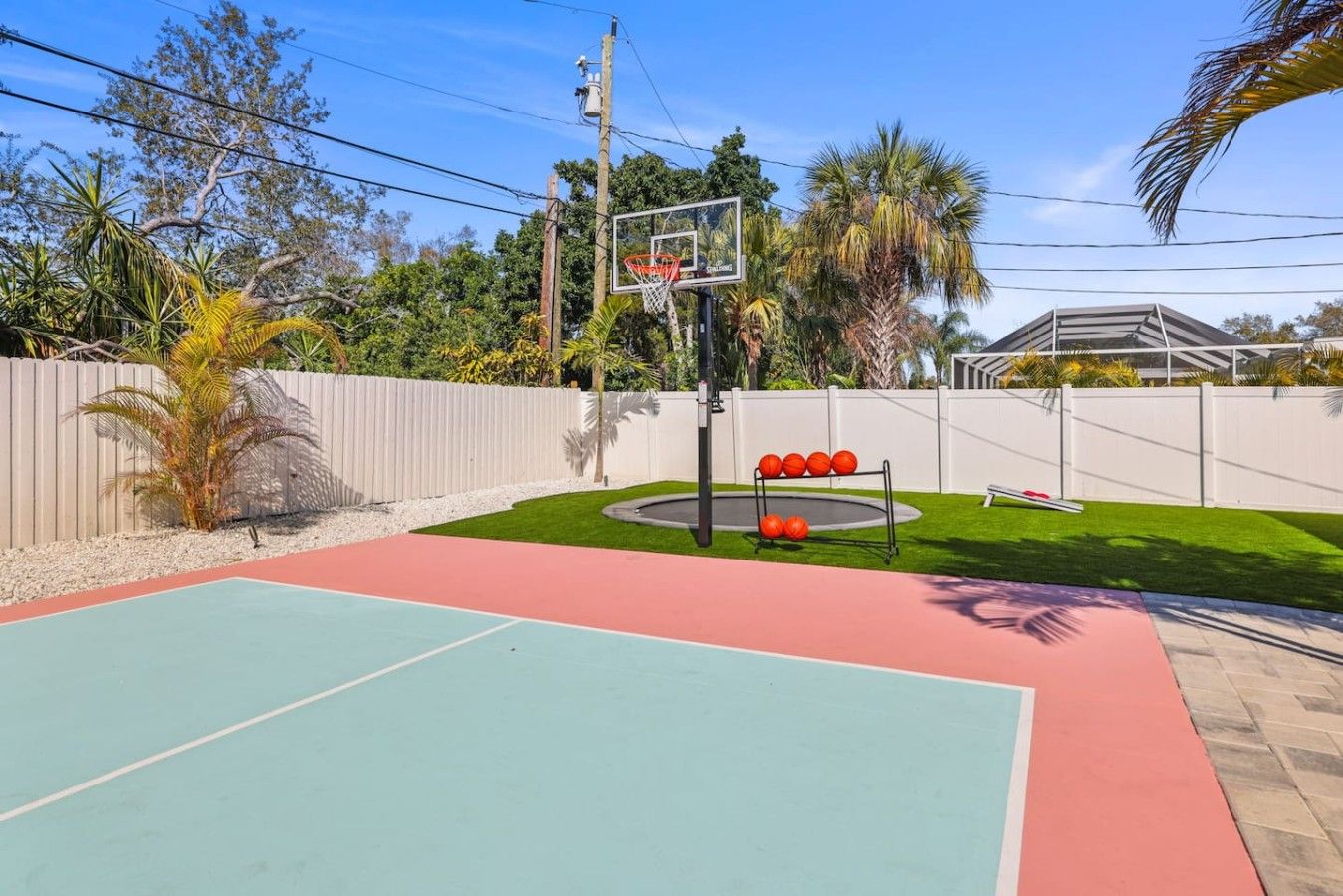 Una cancha de baloncesto al aire libre con un aro, un banco y un carrito de balones.