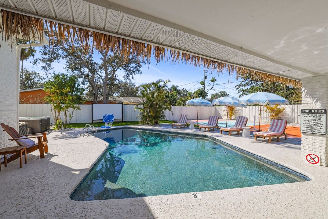 Een zwembad met ligbedden, een jacuzzi en parasols.