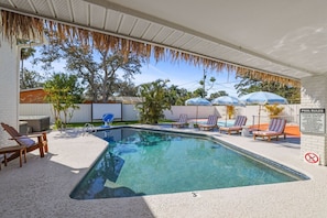 A swimming pool with lounge chairs, a hot tub, and umbrellas.