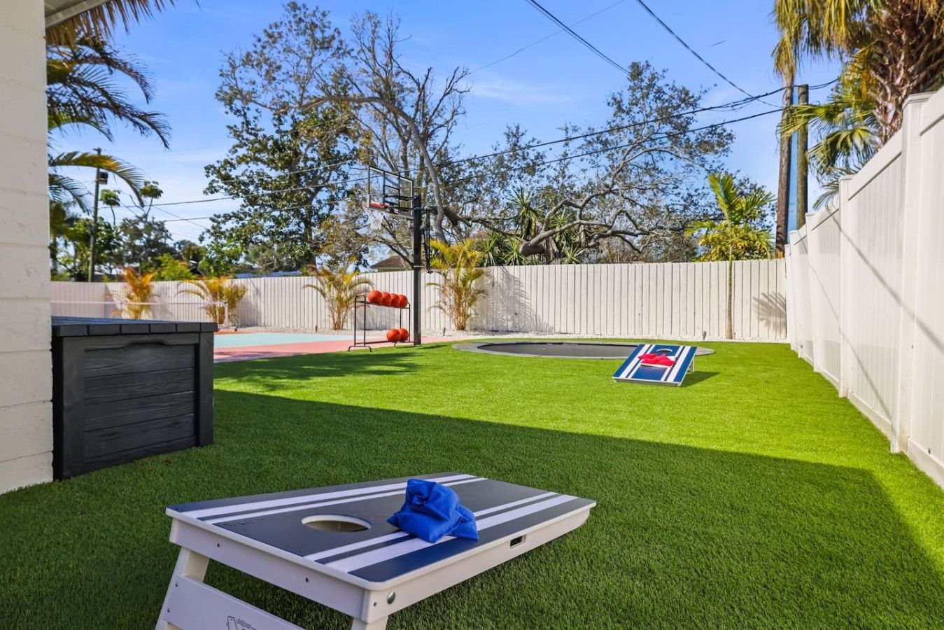 A backyard with artificial grass, a pool, and a tennis court.