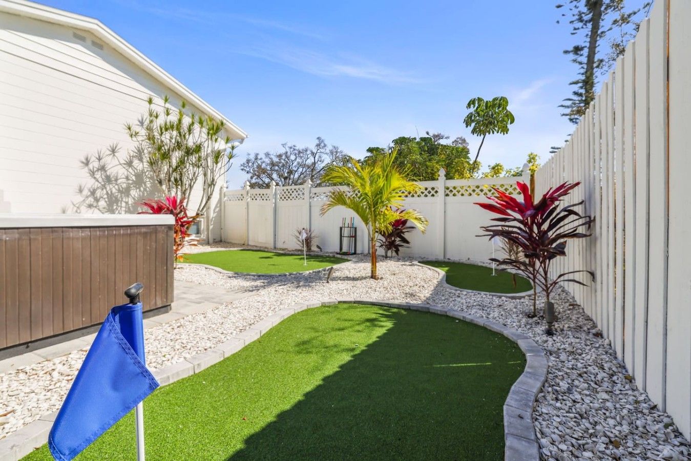 Un patio trasero con césped artificial, una valla de madera y varias plantas.