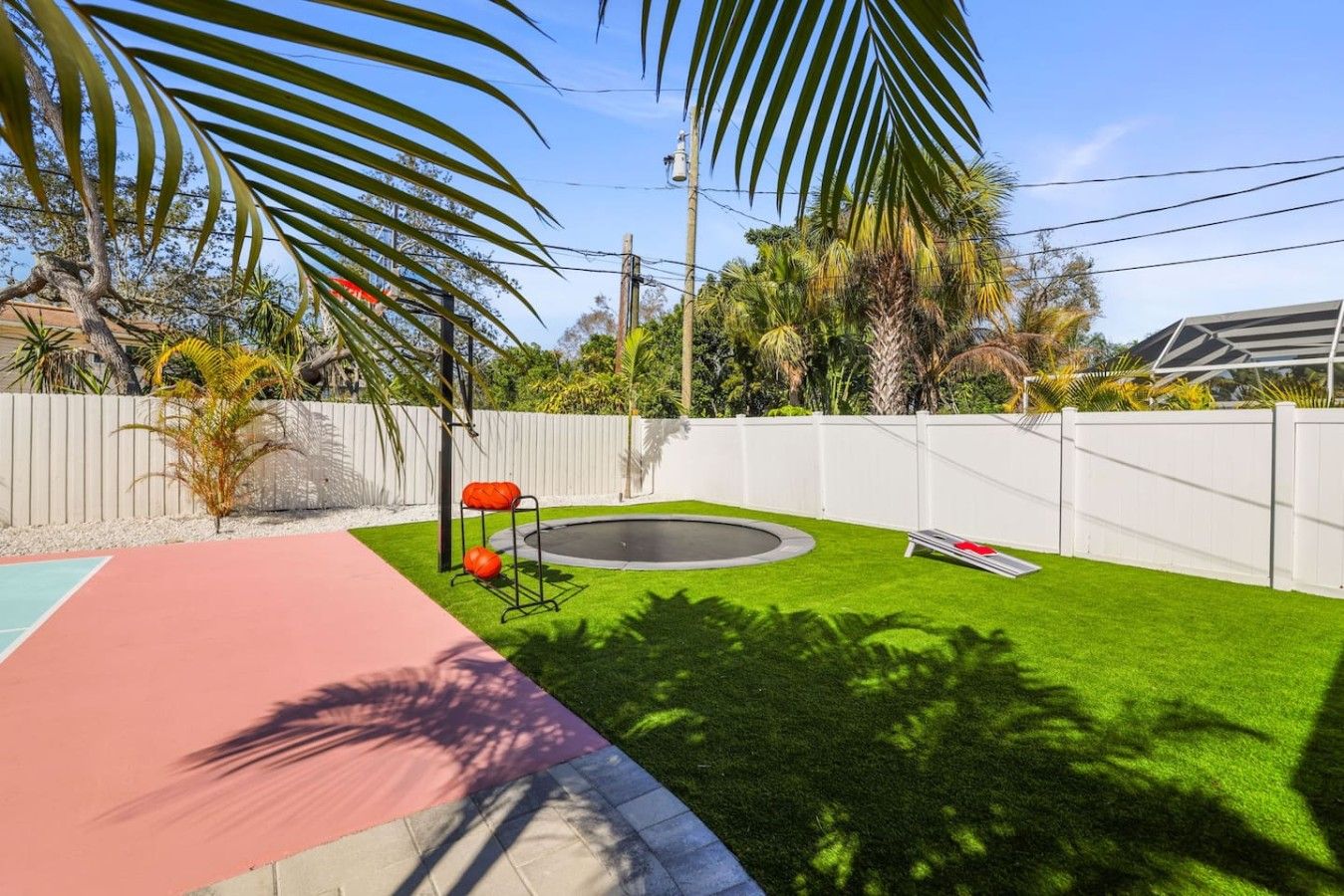 A backyard with a pool, a trampoline, and a small garden area.