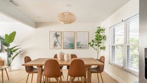 A dining area with a wooden table, six chairs, and a hanging light fixture.