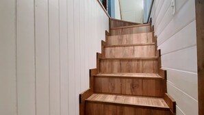 Eine Holztreppe mit weiß umrahmten Wänden, die zu einer Tür oben führt.