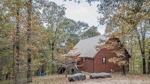 A rustic log cabin surrounded by trees with a dirt path leading to it. - Secluded Cabin w/ Hot Tub Near State Park (Broken Bow)