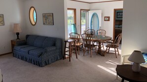 A living room with a sofa, dining table with chairs, and a lamp.