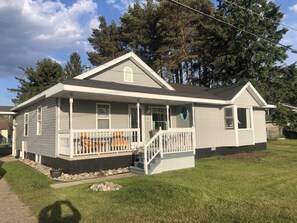 A single-story house with a porch, a small deck, and a stone foundation. - Central located. Includes finished 2 car garage! 1 minute from beach! (Tawas City)