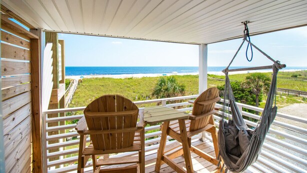 A wooden deck with a table and chairs, a hanging chair, and a view of the ocean. - #3 Just a few steps from Ocean! Incredible Views! (Carolina Beach)