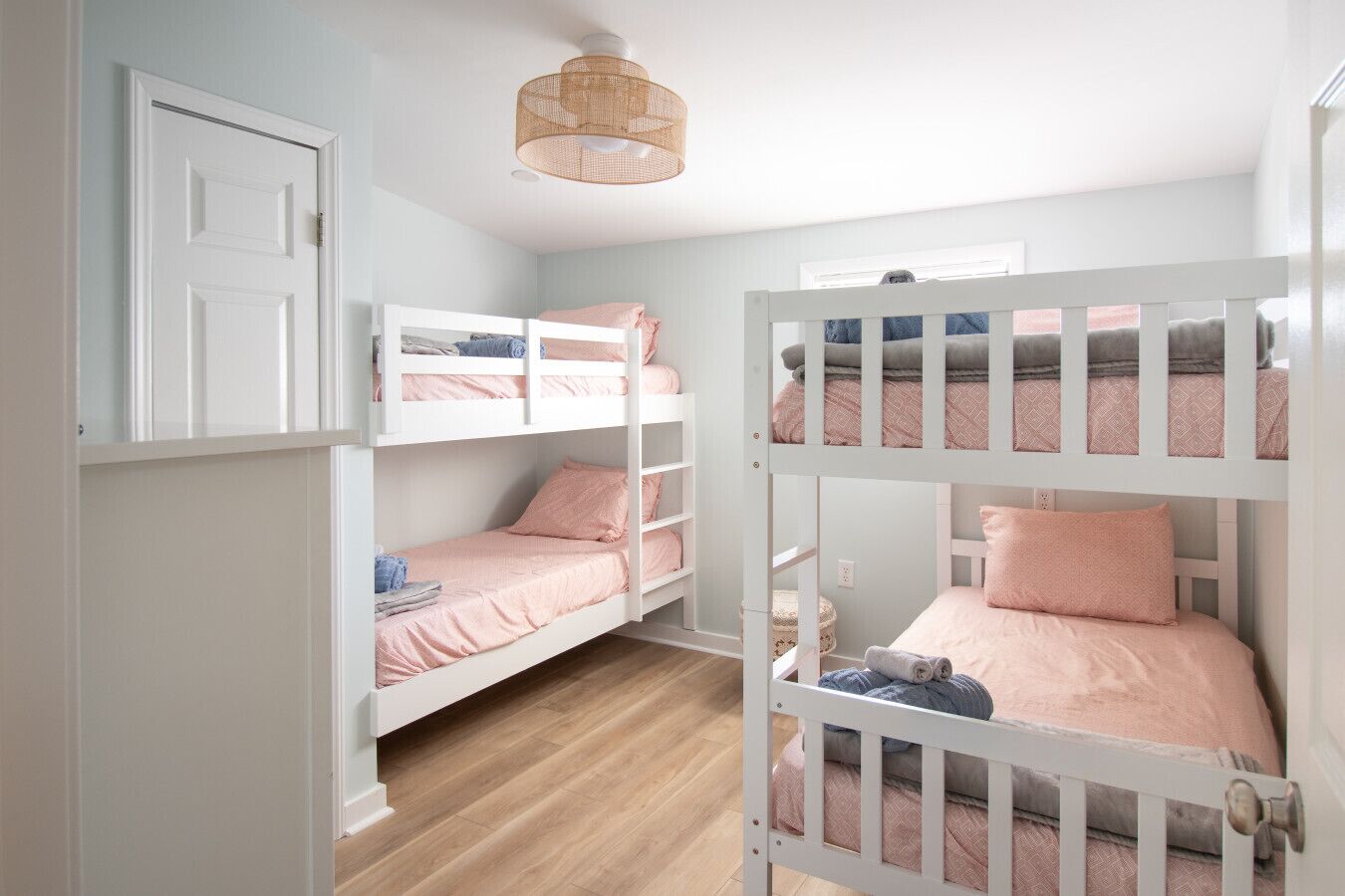 A room with bunk beds, a door, and a hanging light fixture.