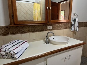A bathroom with a white sink, wooden vanity, patterned tiles, and a yellow shower curtain. - Warrie Head Resort (Ontario Village)