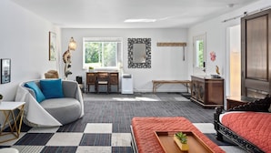 A modern living room with a sofa, a red ottoman, a desk, and a large mirror. - Little Green House
Eclectic Olympic National Park Basecamp, Dogs allowed (Port Angeles)