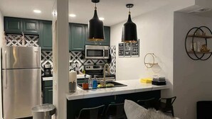 Una cocina moderna con una isla central, electrodomésticos de acero inoxidable e iluminación colgante.