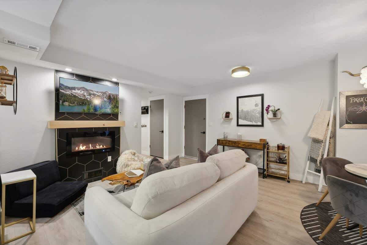 Een moderne woonkamer met een open haard, een flatscreen-tv, een bank en een eethoek.