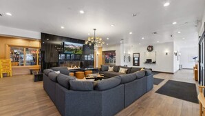 A modern hotel lobby with a large sectional sofa, a fireplace, a television, and a reception desk. - Ski-In Out Mountain Luxury Studio Sleeps 6 (Park City)