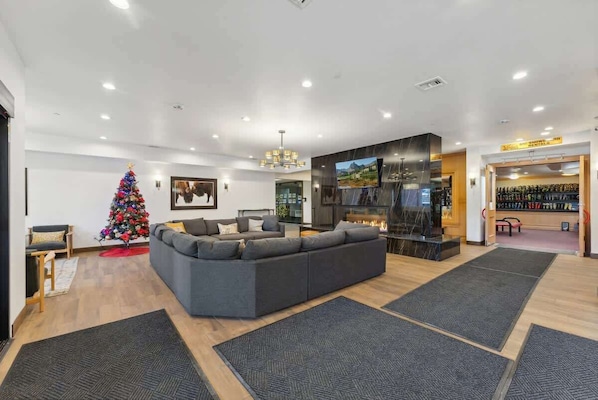 Un salon moderne avec un canapé d’angle, un sapin de Noël et une cheminée.