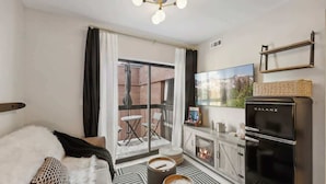 A modern living room with a sofa, a flat-screen TV, a Galanz refrigerator, and a balcony with outdoor furniture. - Ski-In Out Mountain Luxury Studio Sleeps 6 (Park City)