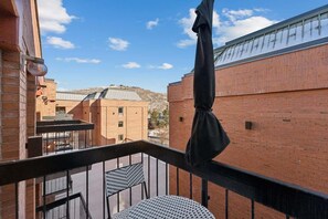 A balcony with a metal railing, a round table, and a hanging object. - Ski-In Out Mountain Luxury Studio Sleeps 6 (Park City)