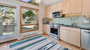 A modern kitchen with wooden cabinets, a stainless steel oven, and a microwave. - Cliffview Luxury Vacation Rental at Windcliff (Estes Park)