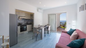 Eine moderne Küche mit Essbereich, einer Couch und Blick ins Freie.
