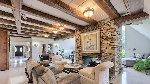 A spacious living room with a stone fireplace, leather sofas, and a dining area with a piano. - Twin Pine Manor Bed & Breakfast (Ephrata)